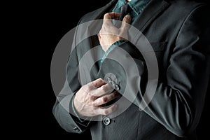 Businessman in green shirt and suit adjusting his black necktie