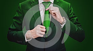 Businessman in green suit tying green necktie. Environment, agriculture and green business