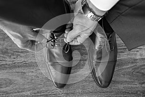 Businessman or groom tying shoe laces preparing