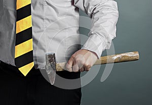 Businessman with hammer in hand and working zone black and yellow stripes cravat