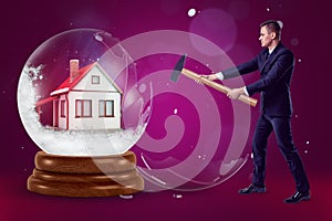 A businessman with a hammer in his hands crashing a crystal ball with a little house inside on a purple background with
