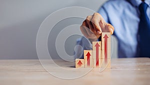 Businessman hand  arranging wood block stacking as step stair with arrow up.concept for business growth success process