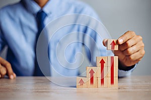 Businessman hand  arranging wood block stacking as step stair with arrow up.concept for business growth success process