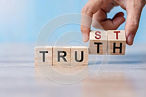 Businessman hand change wooden cube block with TRUST and TRUTH business word on table background. Trustworthy, Truth, beliefs and photo
