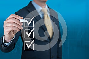 Businessman hand checking the checklist boxes on blue background. Businessman with pen mark the check boxes. Hand choosing one of