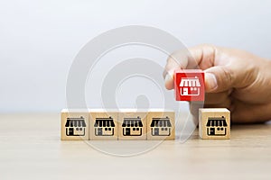 Businessman hand choose wooden blog with franchise marketing icons Store