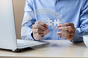 Businessman Hand connecting couple puzzle piece in office. Business solutions, mission, successful, goals and strategy concepts