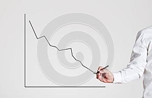 Businessman hand draws a declining line graph