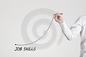 Businessman hand draws a rising line with the word job skills. Increasing business job skills with training or experience