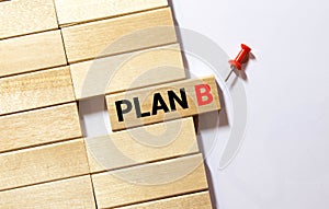 Businessman hand flipping wooden cube blocks with PLAN B text on table background