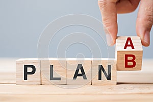 Businessman hand flipping wooden cube blocks with PLAN A change to PLAN B text on table background. strategy, leadership,