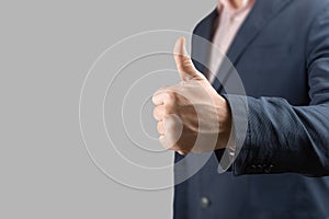 Businessman hand giving thumbs up  on grey background. close up gesturing hand OK isolated on grey. thumbs up man suit