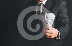 Businessman hand grabbing money, US dollar USD bills on black background