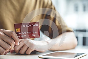 Businessman hand hold credit card to online shopping on computer tablet from home, payment e-commerce, internet banking, spending