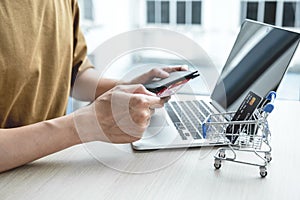 Businessman hand hold credit card to online shopping on laptop computer from home, payment e-commerce, internet banking, spending