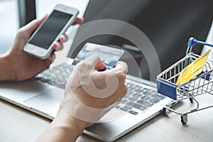 Businessman hand hold credit card to online shopping on laptop computer from home, payment e-commerce, internet banking, spending