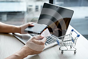 Businessman hand hold credit card to online shopping on laptop computer from home, payment e-commerce, internet banking, spending