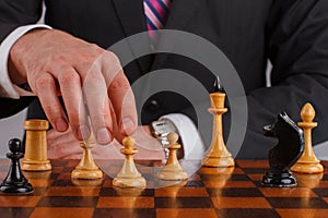 Businessman hand holding a chess piece on a chessboard.