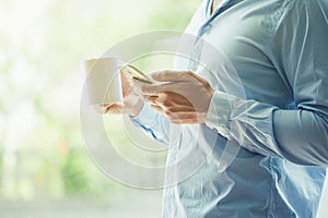 Businessman hand holding coffee and reading phone