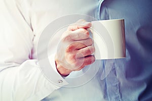 Businessman hand holding coffee or tea mug