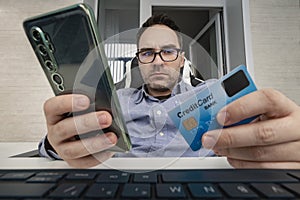 Businessman hand holding credit card to online shopping from home with laptop, payment e-commerce, internet banking, man enters