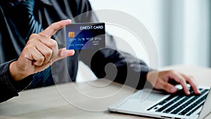 Businessman hand holding credit card to online shopping from home with laptop, payment e-commerce, internet banking, spending