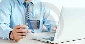 Businessman hand holding credit card to online shopping from home with laptop, payment e-commerce, internet banking, spending