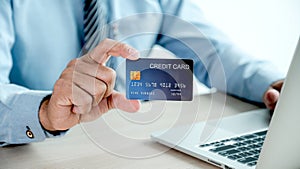 Businessman hand holding credit card to online shopping from home with laptop, payment e-commerce, internet banking, spending