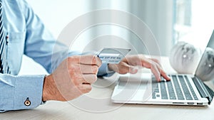 Businessman hand holding credit card to online shopping from home with laptop, payment e-commerce, internet banking, spending