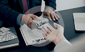 Businessman hand holding dollar bank note money to bribe financial officials or Boss is payout staff salary and anti-bribery
