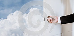 Businessman hand holding door knob, opening to the sky and clouds, with copy space, abstract business concept with copy space