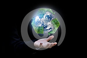 Businessman hand holding Earth and recycle logo over black background.