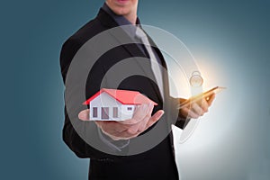 Businessman hand holding house representing home ownership and t