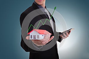 Businessman hand holding house representing home ownership and t