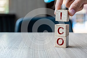 Businessman hand holding ICO Initial Coin Offering word with wooden cube block, is the cryptocurrency industry equivalent to an
