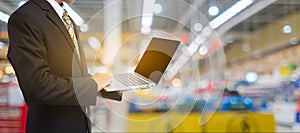 Businessman hand holding laptop in blur supermarket