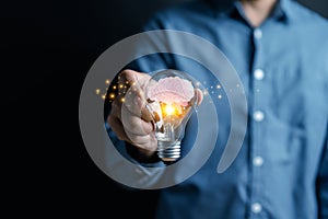 Businessman hand holding light bulb with brain into smart, creative, idea thinking to innovation brainstorm and imagination