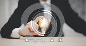 Businessman hand holding light bulb with icon on wood cube and   working on desk, Creativity and innovation are keys to success.Co