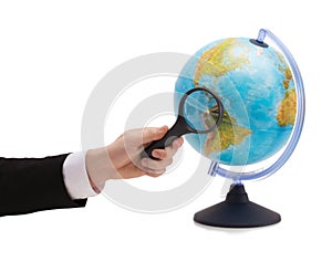 Businessman hand holding magnifier over globe