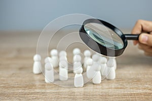 Businessman hand holding magnifying glass for recruiting leader man wooden from crowd of employees. People, Business, Human