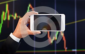 Businessman hand holding mobile phone  with empty screen with stock market graph background