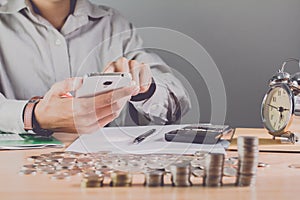 Businessman hand holding mobile phone on the table with a medal recognizing computation and. Sunset light Business Background