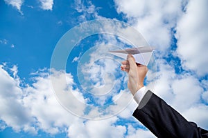 Businessman hand holding paper plane on sky Background.