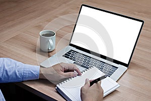 Businessman hand holding a pen to paperwork with white screen background mock up on display laptop with clipping path