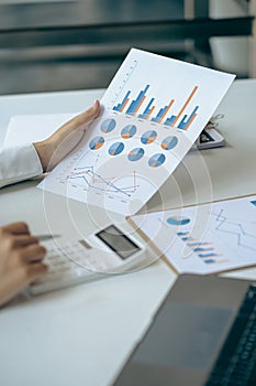 Businessman hand holding a pen to work with charts, graphs and analyze business strategies. financial statistics with laptop sit a