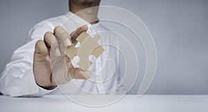 Businessman hand holding and showing jigsaw puzzle piece.