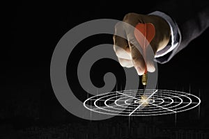 Businessman hand holding and trowing red dart to target board on black background.Business and investment target concept