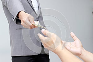 Businessman hand holding US dollar, USD. bills, offers dollar bank note money and giving money Paid for Something by Cash in Busin