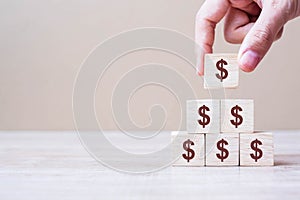 Businessman hand holding wooden blocks with the American Dollar symbol. Money, cash, currency and investment concept