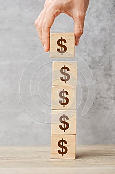 Businessman hand holding wooden blocks with the American Dollar symbol. Money, cash, currency and investment concept